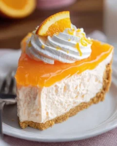 Slice of orange Jello Creamsicle Pie with whipped cream and orange zest garnish