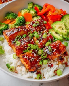 Teriyaki glazed salmon rice bowl garnished with vegetables and sesame seeds