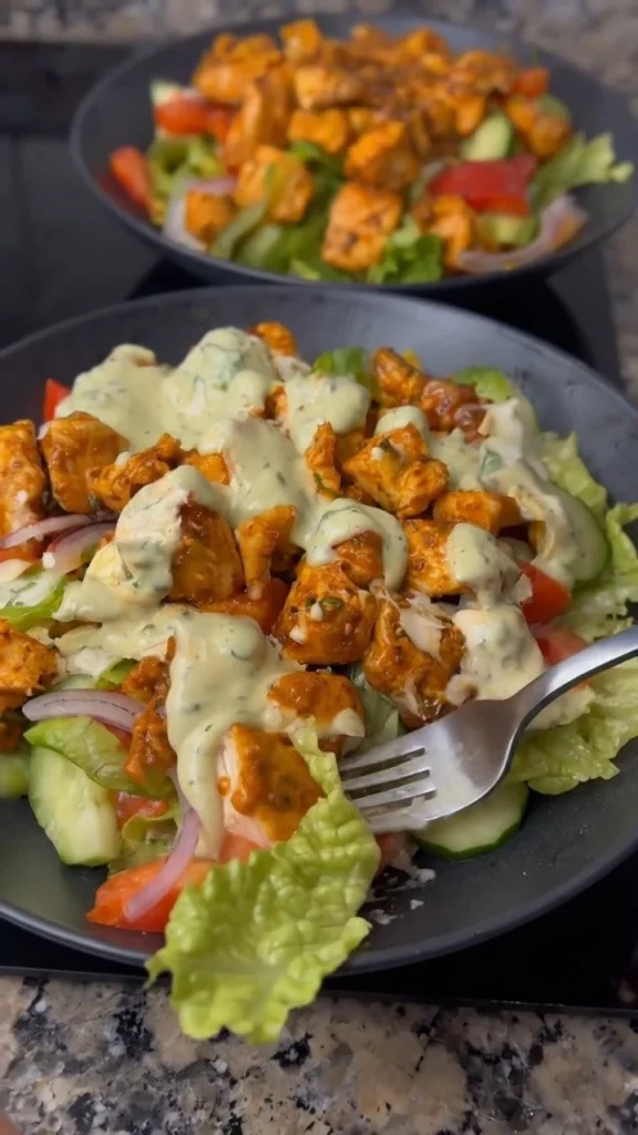 A colorful bowl of chicken salad with fresh vegetables and a tangy dressing